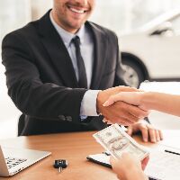 Salesman and person shaking hands while the person holds cash
