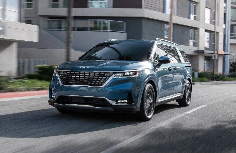 2022 Kia Carnival blue driving down city street