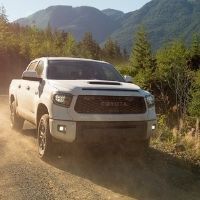 front view of a Toyota truck in mud between greenery