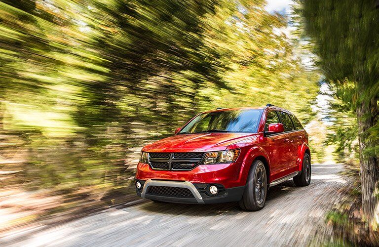 red 2017 Dodge Journey driving through the wood so fast everything else is blurred