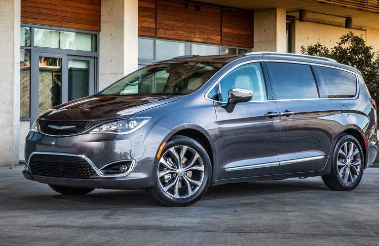 side view of a silver 2018 Chrysler Pacifica in front of a fancy office building