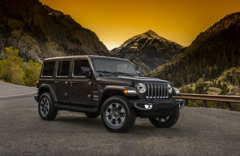 side view of a dark 2018 Jeep Wrangler Unlimited with mountains in the background