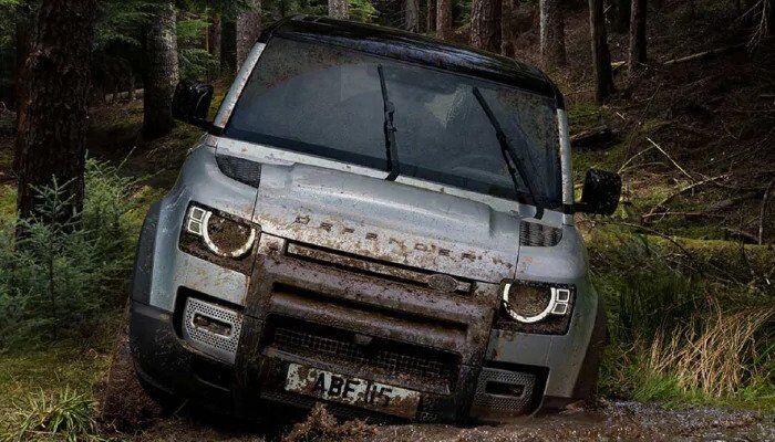 Land Rover Defender driving through muddy forest