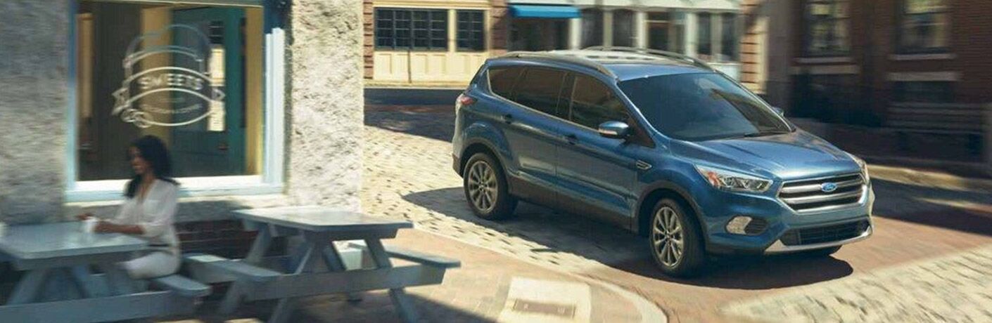 Blue 2019 Ford Escape driving on cobblestone city road