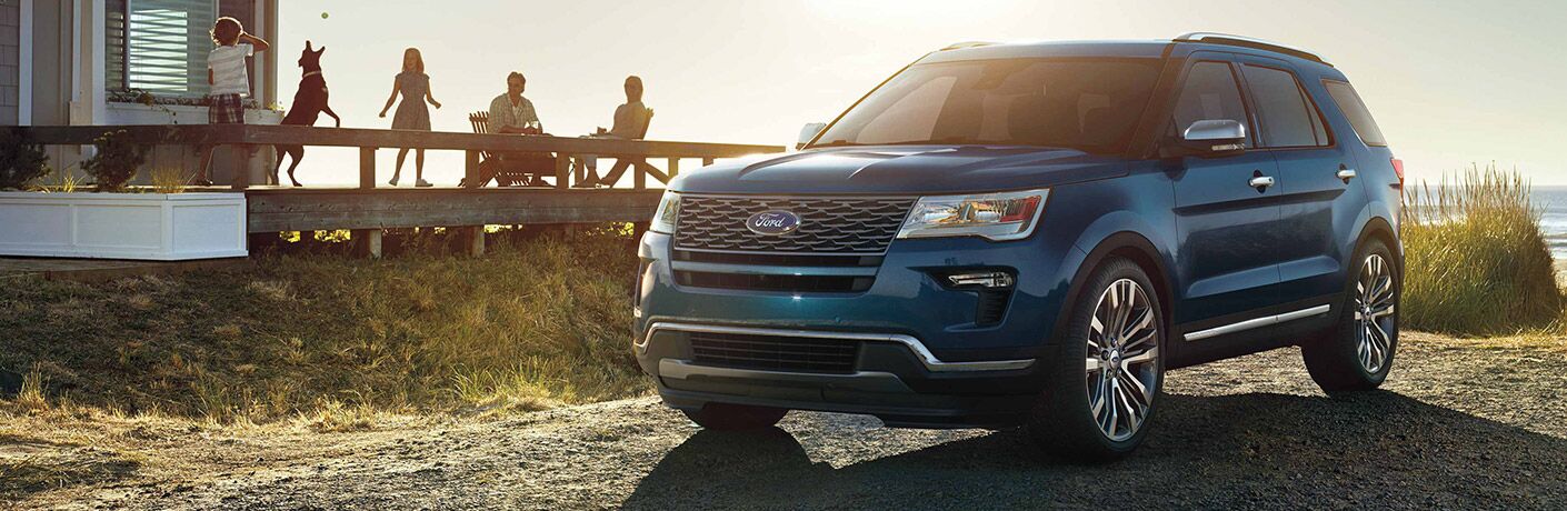 Group of people and dog looking at 2019 Ford Explorer parked in front of beach house