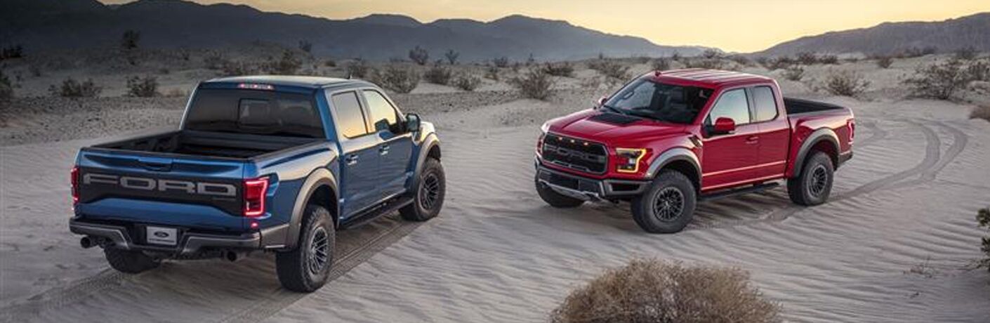 Two 2019 Ford F-150 Raptor models parked in sand