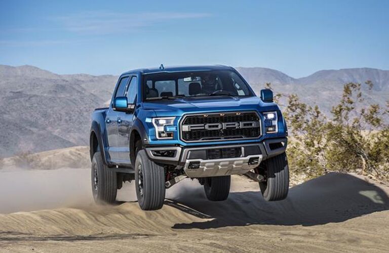 Blue 2019 Ford F-150 Raptor jumping over hill