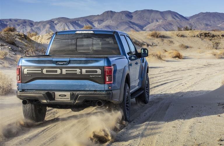 Rear shot of blue 2019 Ford F-150 Raptor driving on trail