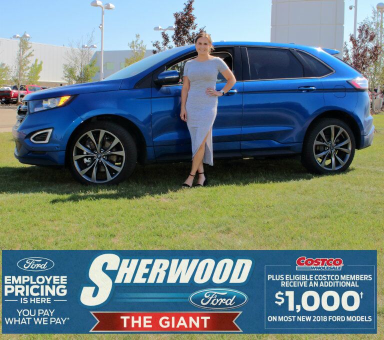Katherine from Sherwood Ford standing in front of blue 2018 Ford Edge