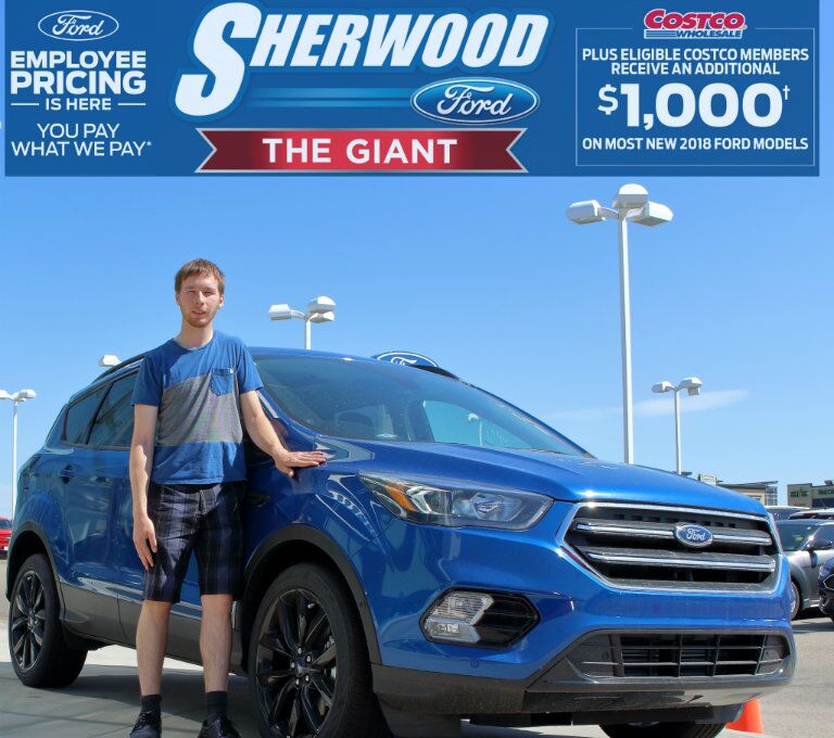 Alex from Sherwood Ford standing in front of blue 2018 Ford Escape