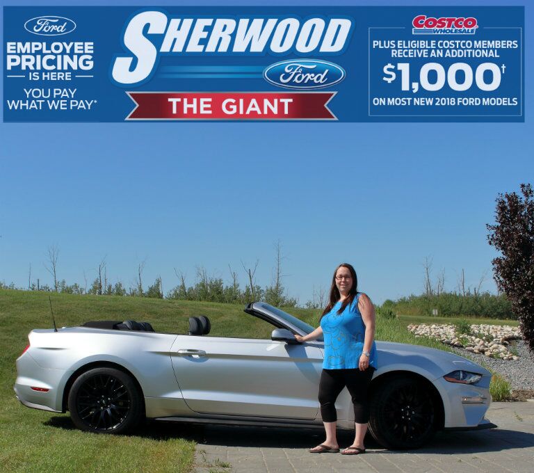 Brandi from Sherwood Ford standing in front of 2018 Ford Mustang convertible