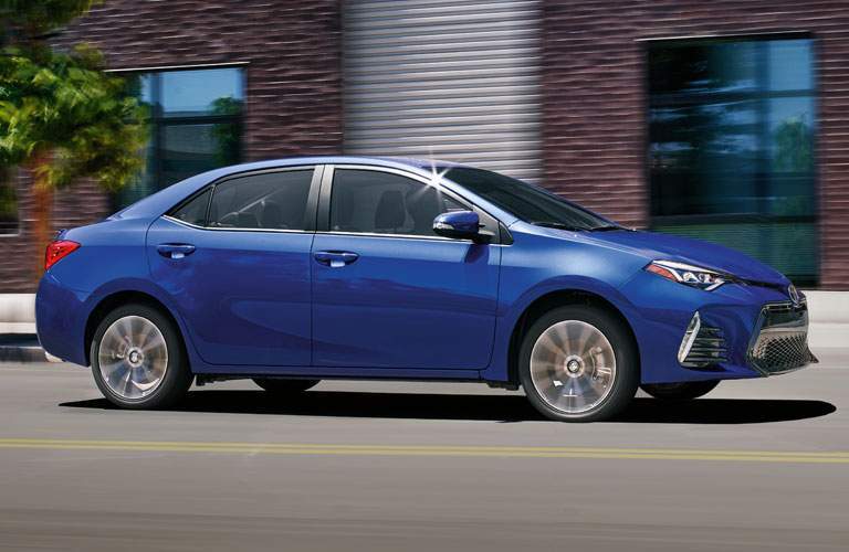 blue toyota corolla near brick building