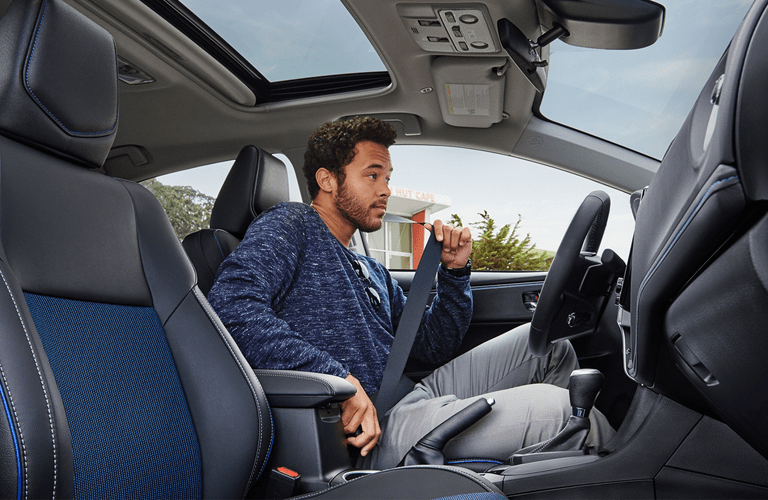 Man fastening seat belt in Toyota Corolla