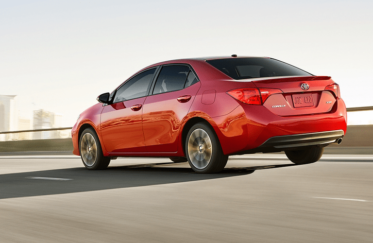 Red Toyota Corolla driving on empty road