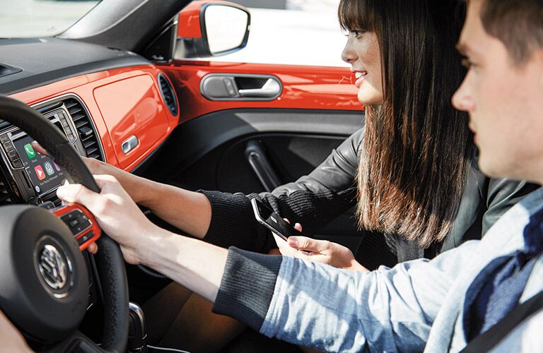 Two people connecting Apple CarPlay technology with their smartphone