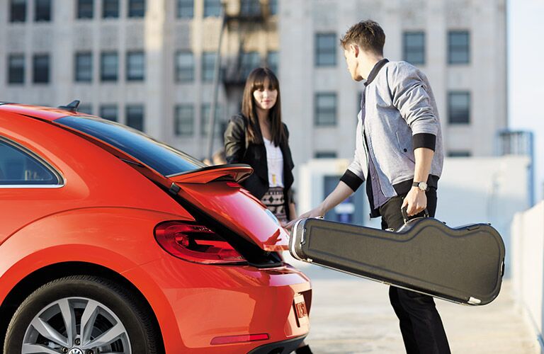 Two people taking music equipment out of the 2016 VW Beetle's trunk