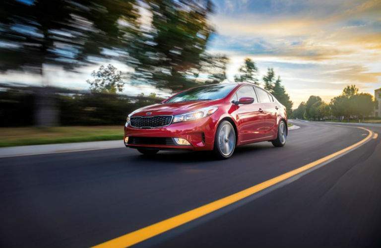 red kia forte driving fast down road