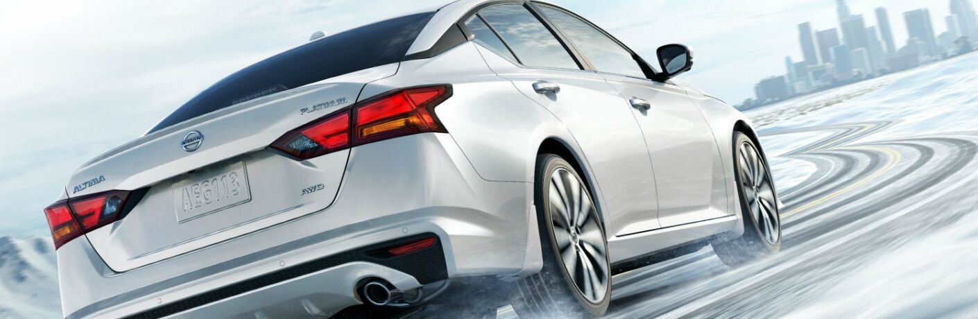 white 2019 Nissan Altima driving toward skyscrapers