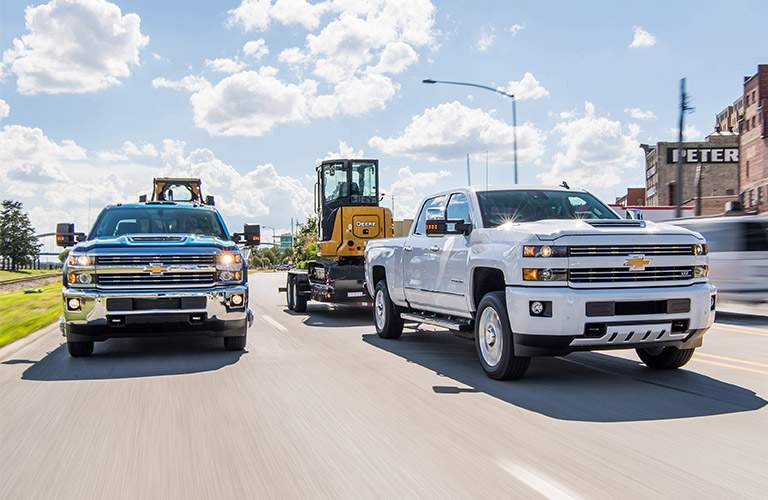 Two 2018 Chevy Silverado 2500HD trucks towing trailers