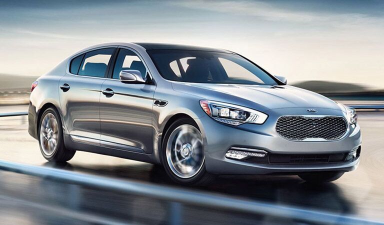 Kia K900 Driving Down Road Side and Front End View in Silver