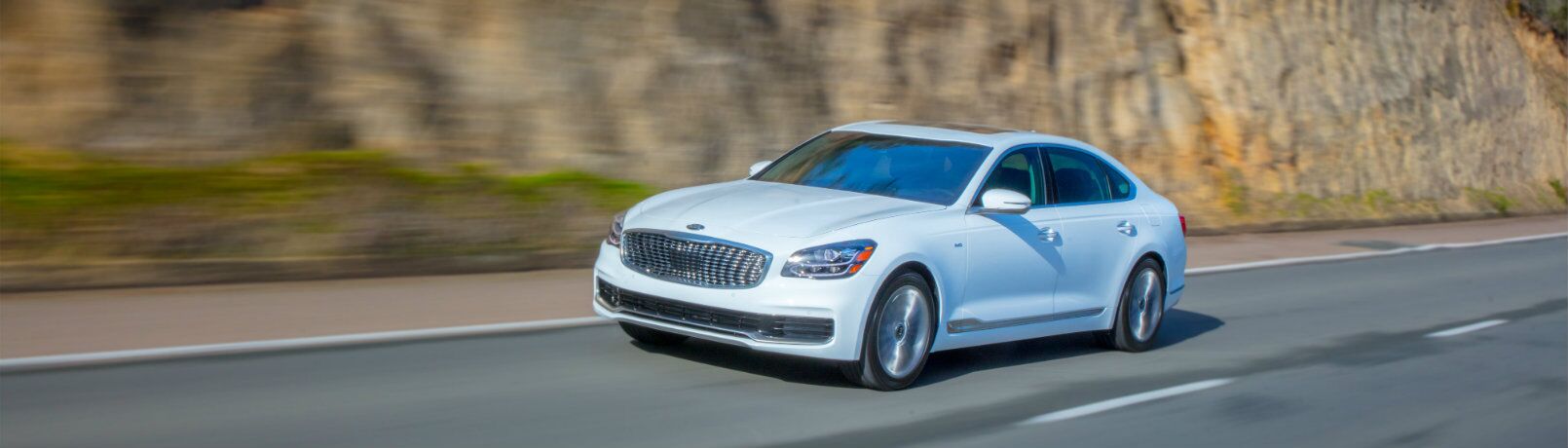 2019 Kia K900 driving near a mountain