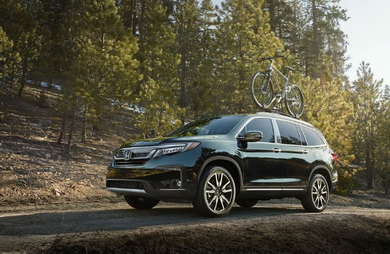front of 2019 honda pilot in the woods with a bike on the roof