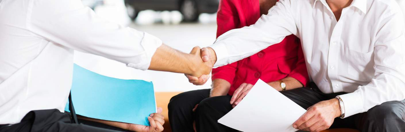 Older Couple Shaking Hands with a Car Salesman