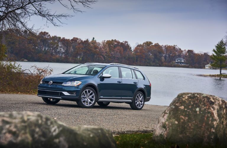 A left profile photo of the 2018 VW Golf Alltrack parked in front of lake.