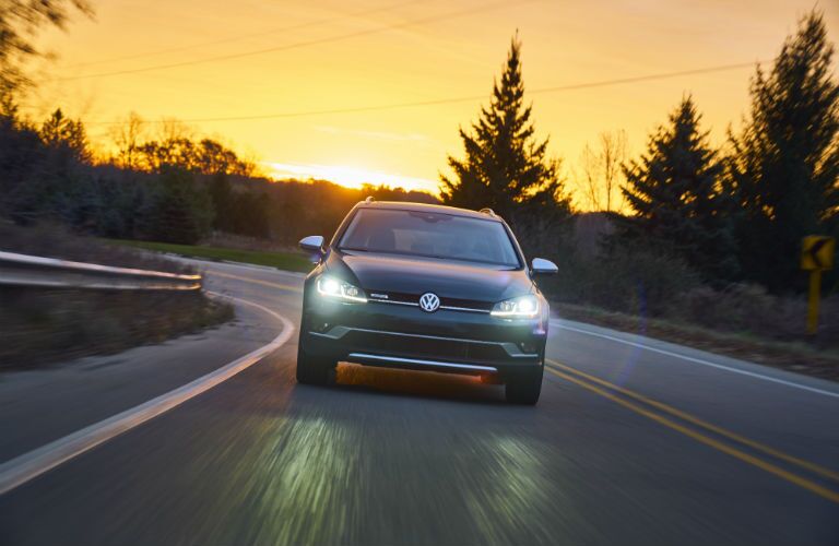 A head-on photo of the 2018 VW Golf Alltrack on the road at sunset.