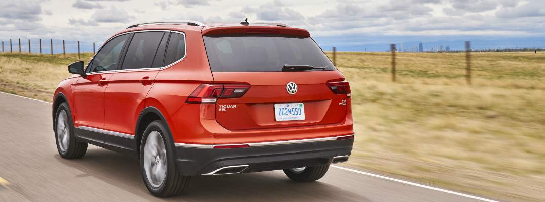 A rear quarter view of a 2018 VW Tiguan traveling down a country road
