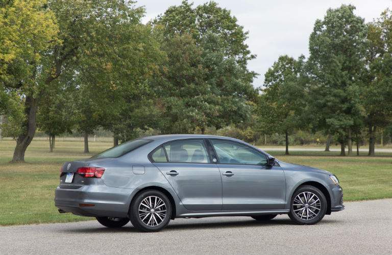A right profile view of a gray 2018 Volkswagen Jetta in a wooded parking lot