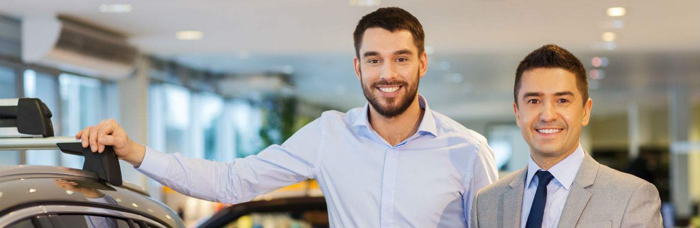 A young man standing next to a sales person in a suit tie
