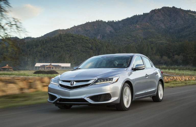 A front left quarter view of a gray 2018 Acura ILX driving over a country road