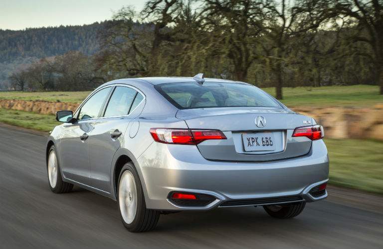 A rear quarter view of the 2018 Acura ILX driving through the country.