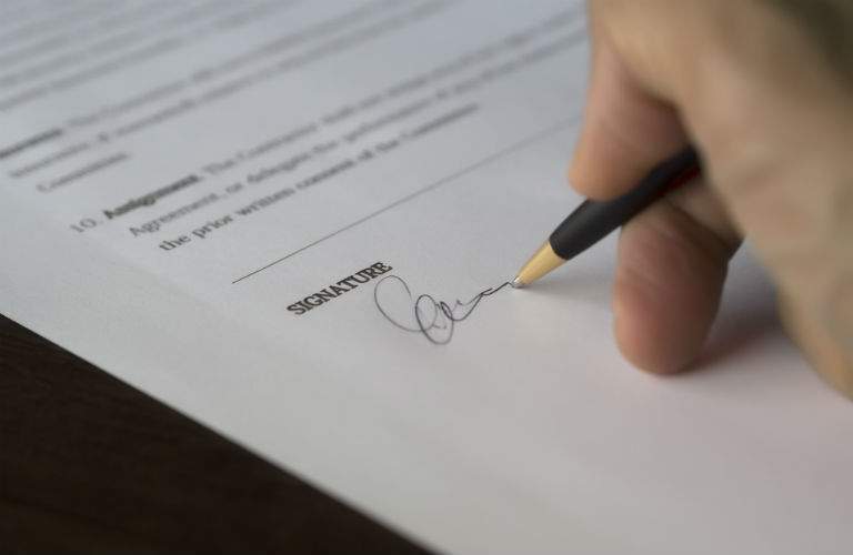 A stock photo of a person signing paper work.
