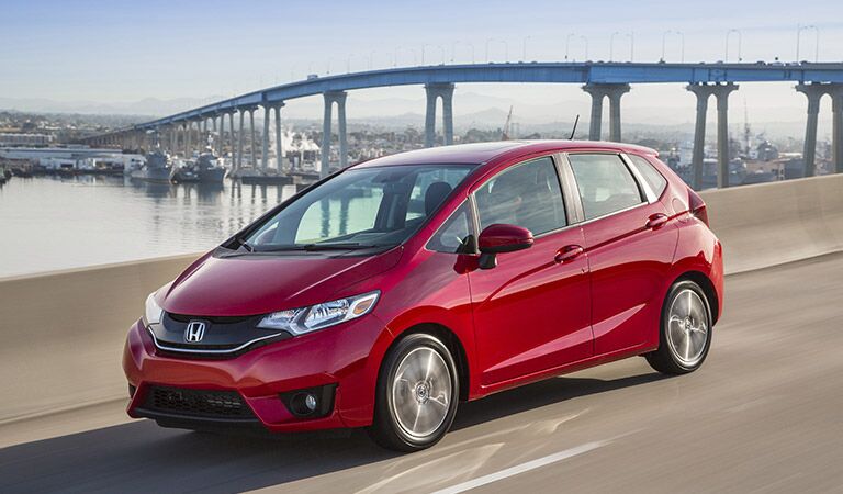 red 2017 Honda Fit on the road in front of a bridge