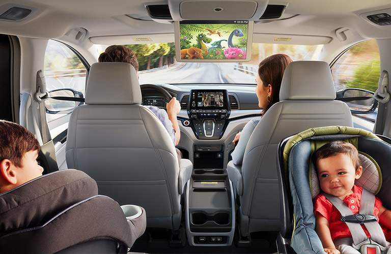 view of the front two rows of the 2018 Honda Odyssey EX with child seats and children in the second row