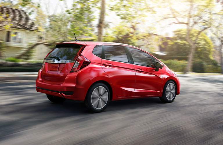 red 2018 Honda Fit hatchback driving down a residential street