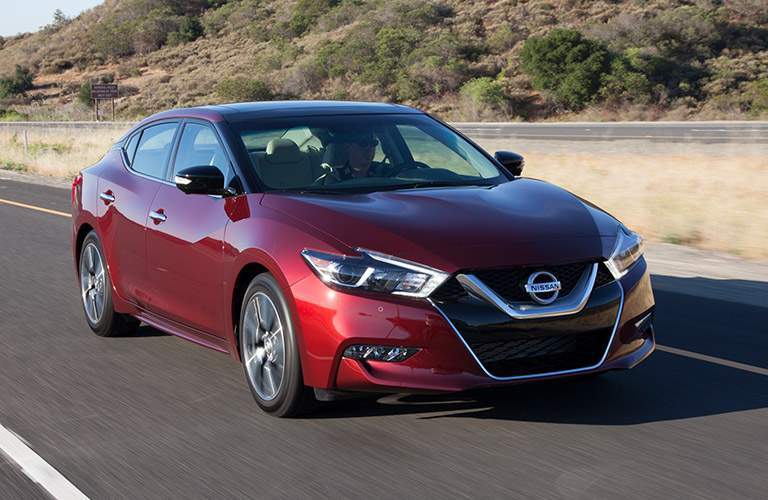 red 2018 nissan maxima driving on desert highway