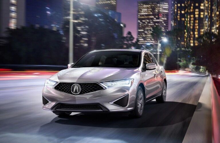 Front driver angle of a silver 2020 Acura ILX driving down a city street
