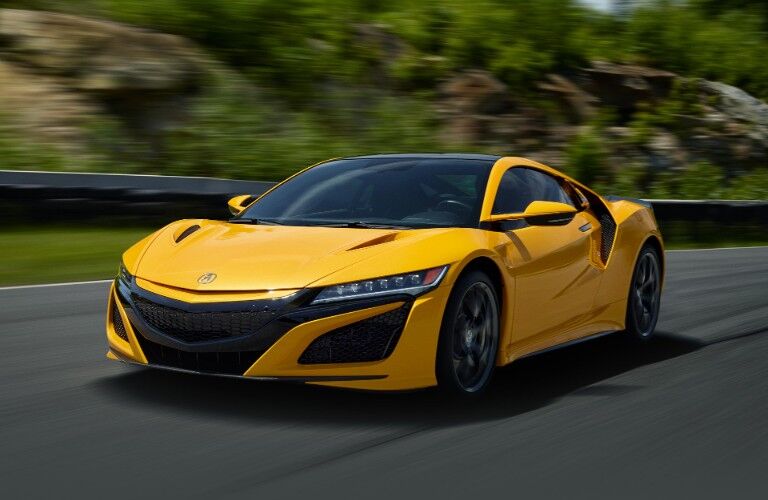 Front driver angle of a yellow 2020 Acura NSX driving down a road