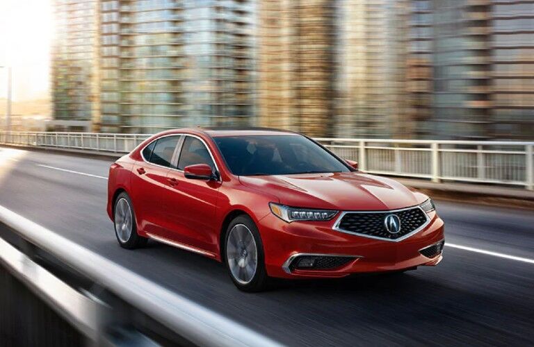 Front passenger angle of a red 2020 Acura TLX driving in a city