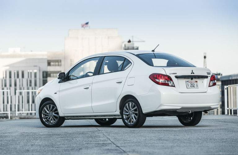A left rear quarter photo of a white 2018 Mitsubishi Mirage G4 on top of a parking garage