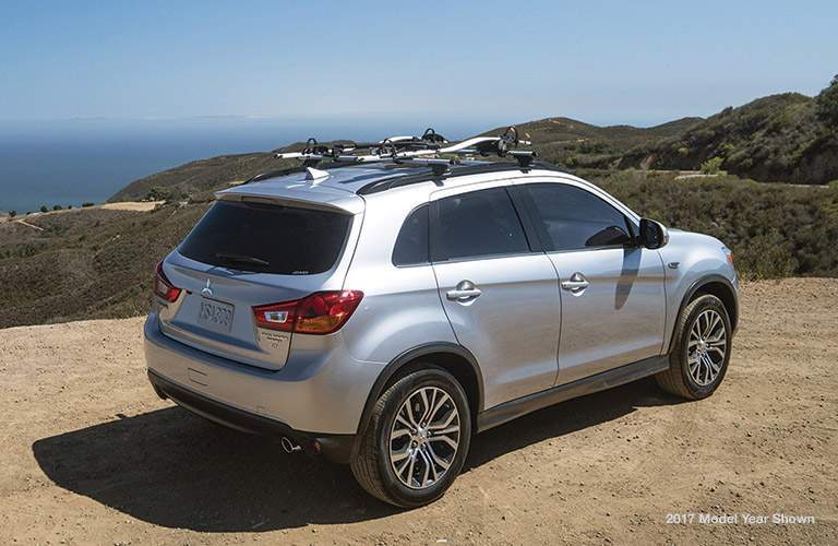 A silver 2018 Mitsubishi Outlander Sport overlooking mountains and the ocean with a rear quarter view of the vehicle