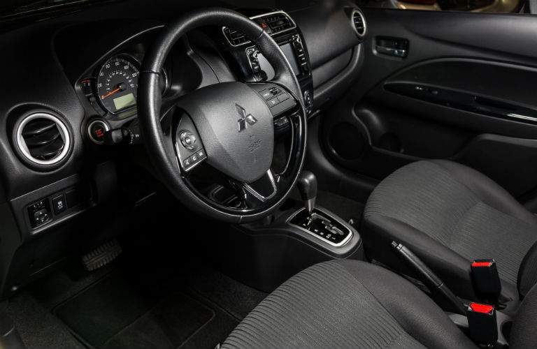 A view from the driver's side of the 2018 Mitsubishi Mirage G4 showing the steering wheel and center gauge cluster