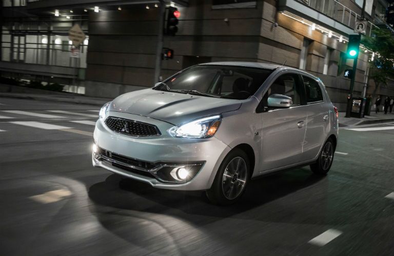 A front left quarter photo of the 2018 Mirage driving through the city at night with its lights on.