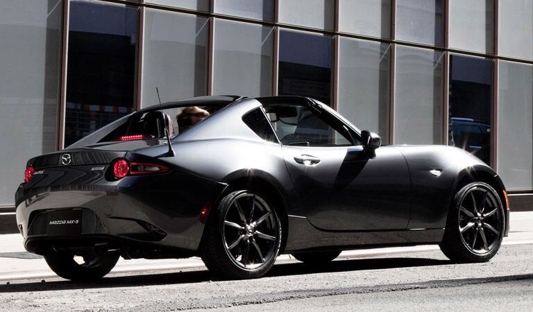 rear side view of the 2017 Mazda MX-5 Miata driving with the top down