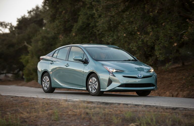 A front right quarter photo of the 2018 Toyota Prius in motion on the road.