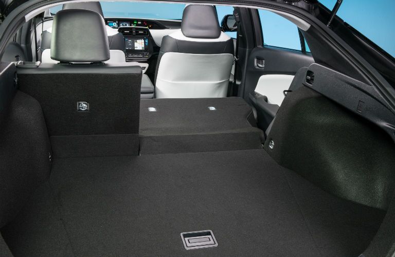 An interior photo of the rear seats partially folded down in the 2018 Prius.