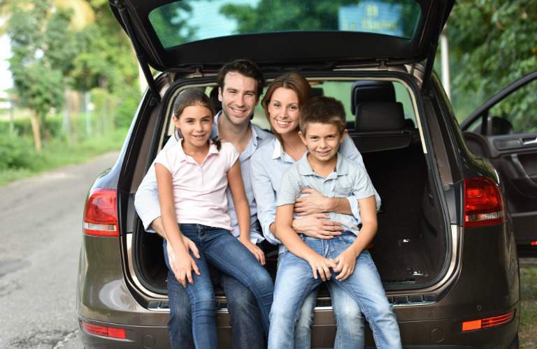 Family of four sitting on the back end of their car